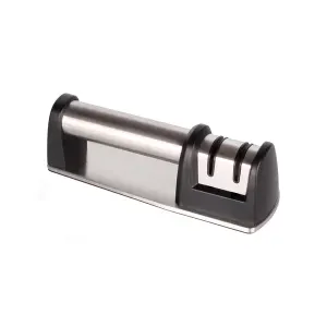 "Truper 15147 manual knife sharpener with two sharpening stages for precision. The sharpener features a durable plastic body, ergonomic handle, and two ceramic wheels for coarse and fine sharpening. Ideal for maintaining kitchen knives, it provides a secure, easy-to-use grip while restoring blade sharpness efficiently. Compact and portable design for convenient storage."