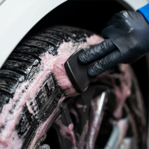 Car tire being cleaned with foam and brush at Sakr Building Materials.