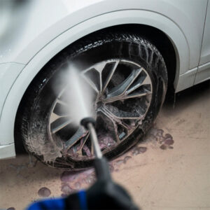 Car wheel being cleaned with a pressure washer at Sakr Building Materials store.