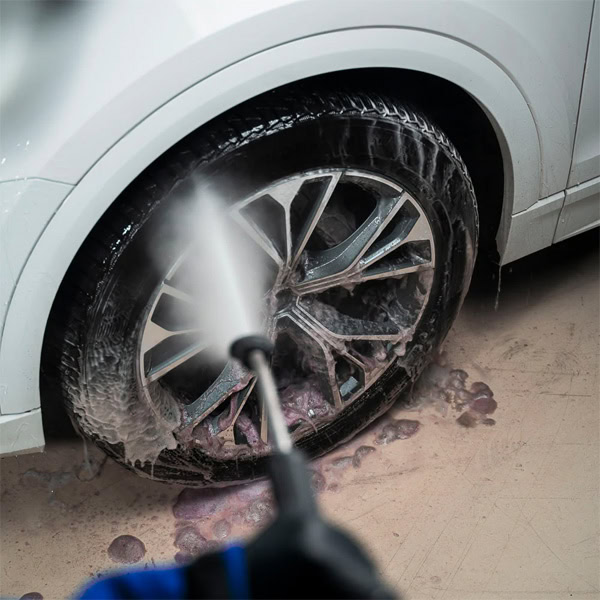 Car wheel being cleaned with a pressure washer at Sakr Building Materials store.