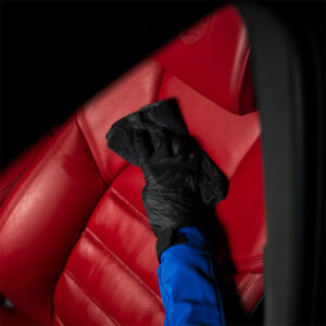 Professional car interior cleaning with microfiber cloth and gloves for spotless seats.