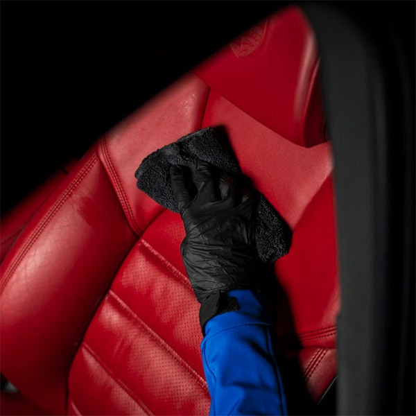 Professional car interior cleaning with microfiber cloth and gloves for spotless seats.