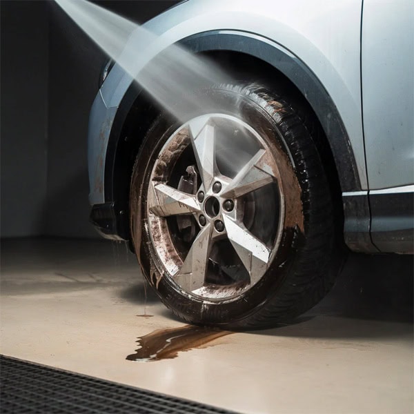 Car wheel cleaning using water spray at a car wash station.
