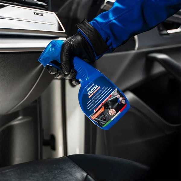 Car interior cleaning spray in use for vehicle maintenance and detailing.