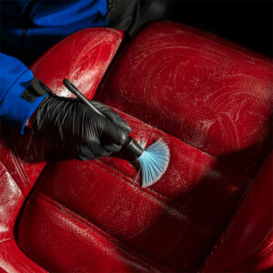 Professional car upholstery cleaning using brush and vacuum for deep stain removal.
