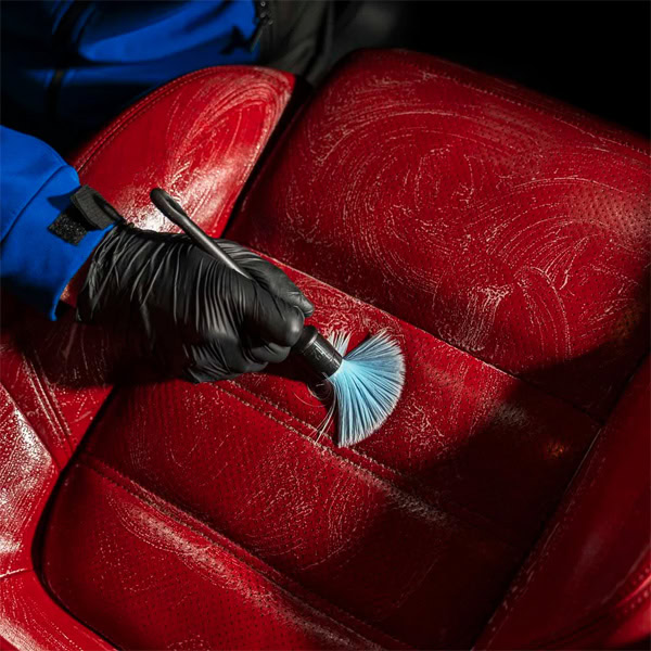 Professional car upholstery cleaning using brush and vacuum for deep stain removal.