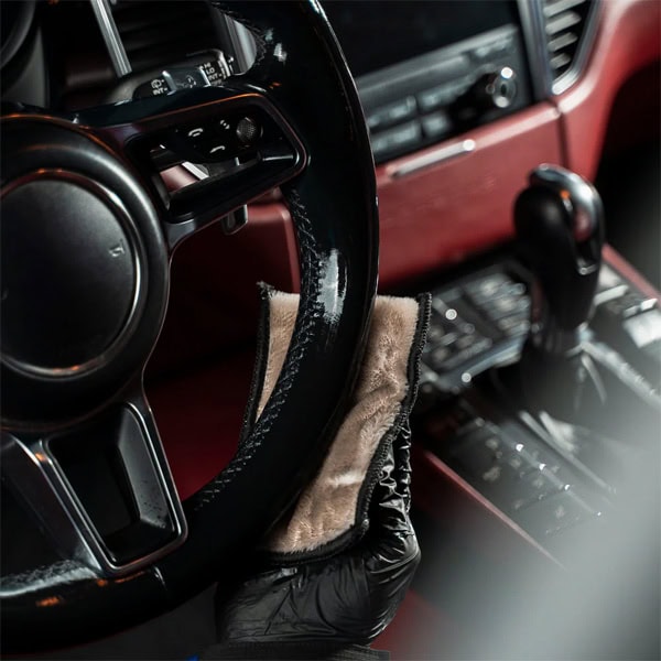Interior cleaning of a vehicle with disinfectant cloth and protective gloves.