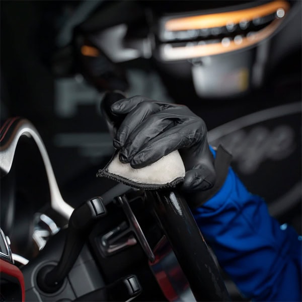 Cleaning car dashboard and steering wheel with microfiber cloth.