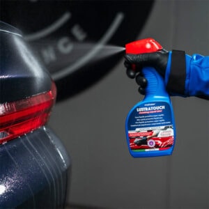 Car scratch remover spray being applied to vehicle's rear bumper for auto detailing.