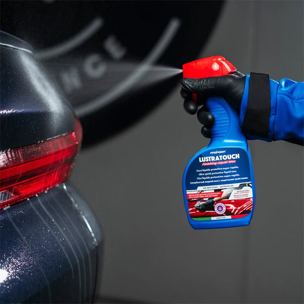 Car scratch remover spray being applied to vehicle's rear bumper for auto detailing.