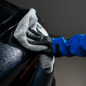 Hand polishing a car with microfiber cloth, close-up of car detailing process.