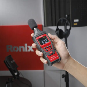 Hand holding a sound level meter measuring 37.2 dB in a construction site.